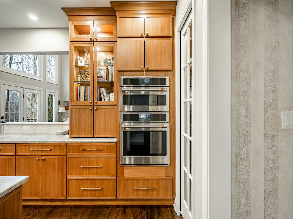 Café stainless double wall oven with built-in microwave flanked by lit glass-front display cabinets in West Chester PA kitchen remodel
