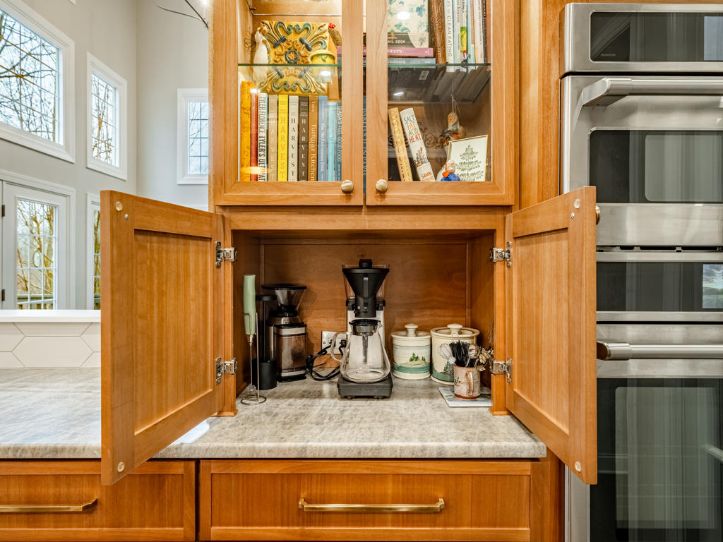 Custom appliance garage open revealing built-in coffee station with quartzite countertop surface and dedicated electrical in West Chester kitchen