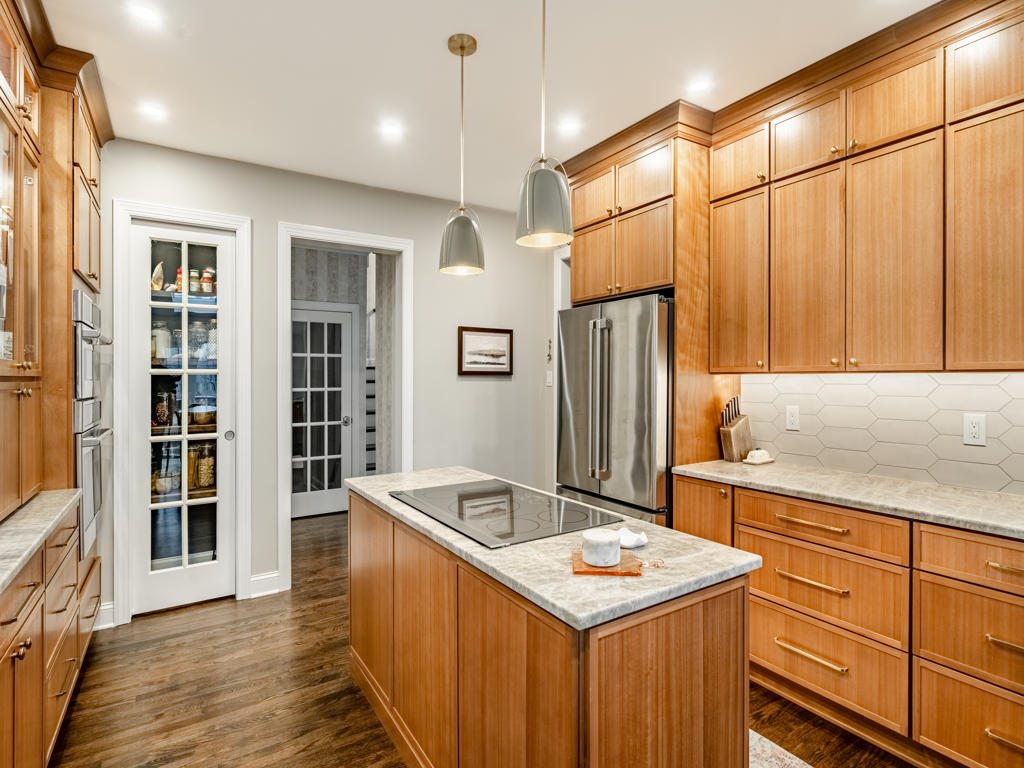 Custom refinished hardwood flooring throughout West Chester kitchen and first floor showing warm oak tone against maple cabinetry and leathered quartzite island