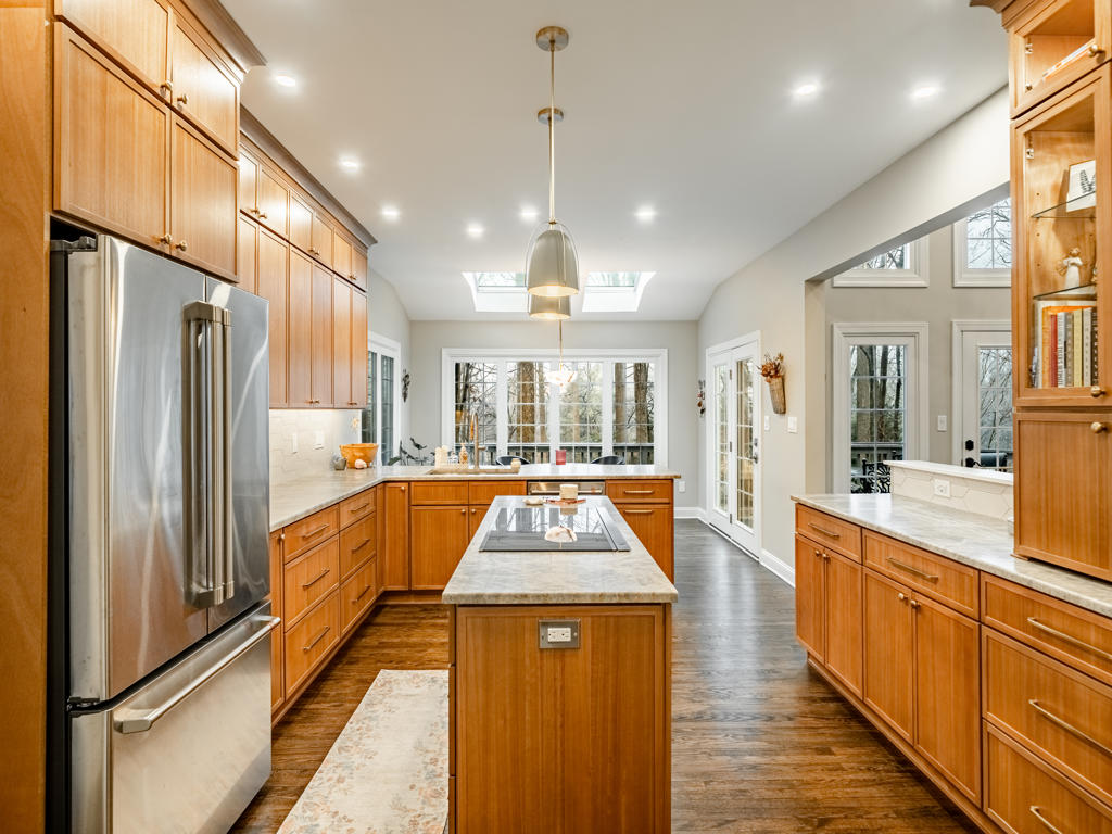 West Chester kitchen remodel with leathered quartzite island, downdraft cooktop, maple shaker cabinetry, twin skylights, and brushed dome pendants