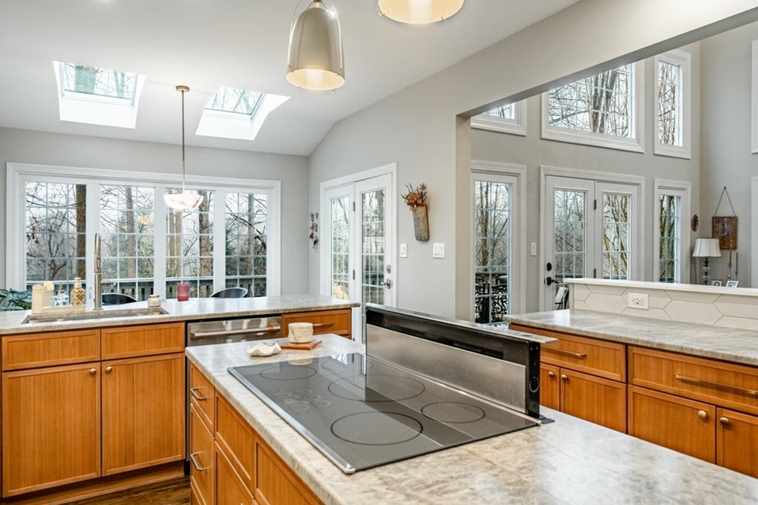 Leathered quartzite island with integrated downdraft cooktop and brushed dome pendants in West Chester kitchen