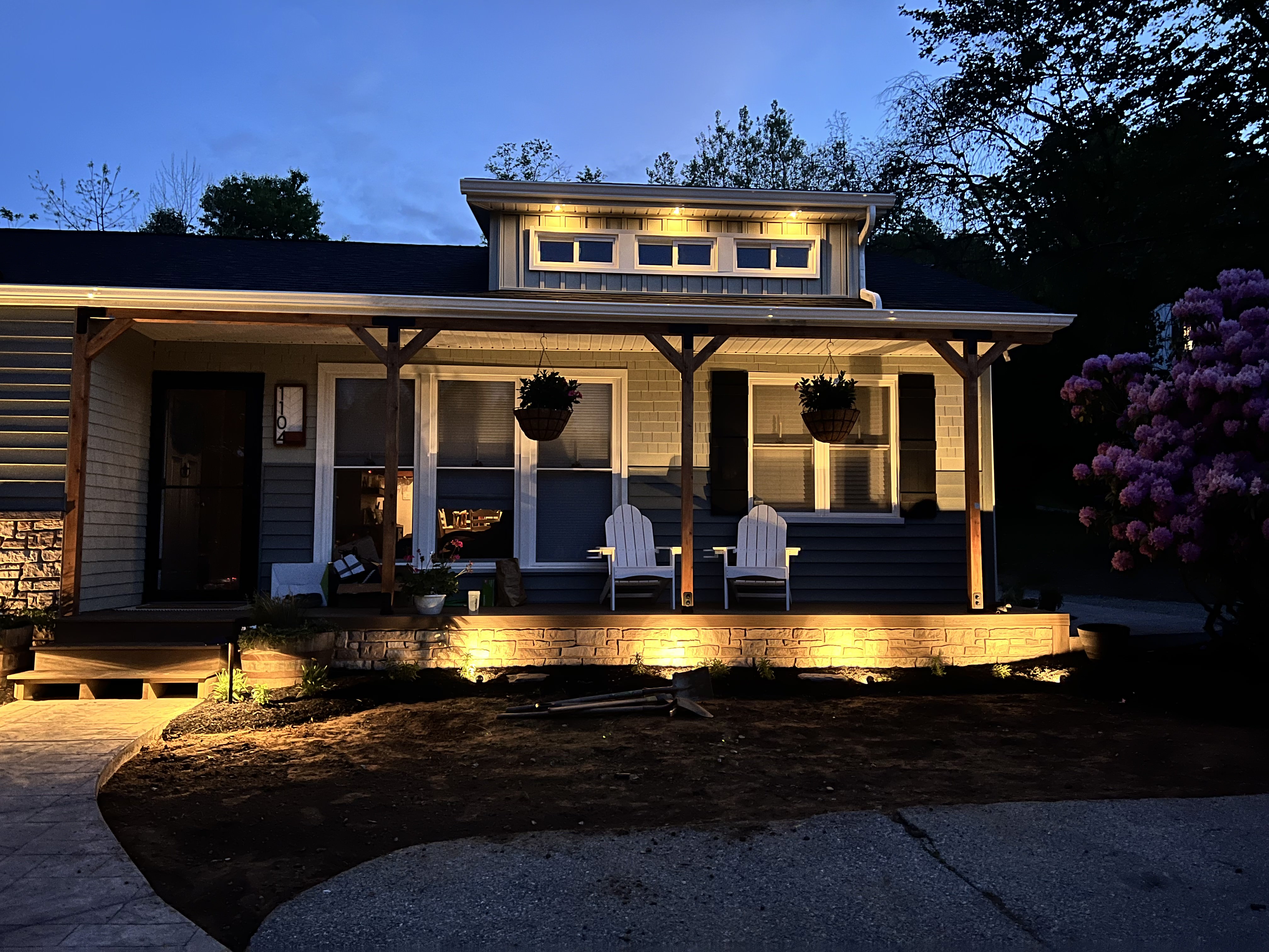 Front porch at dusk with warm lighting and illuminated dormers