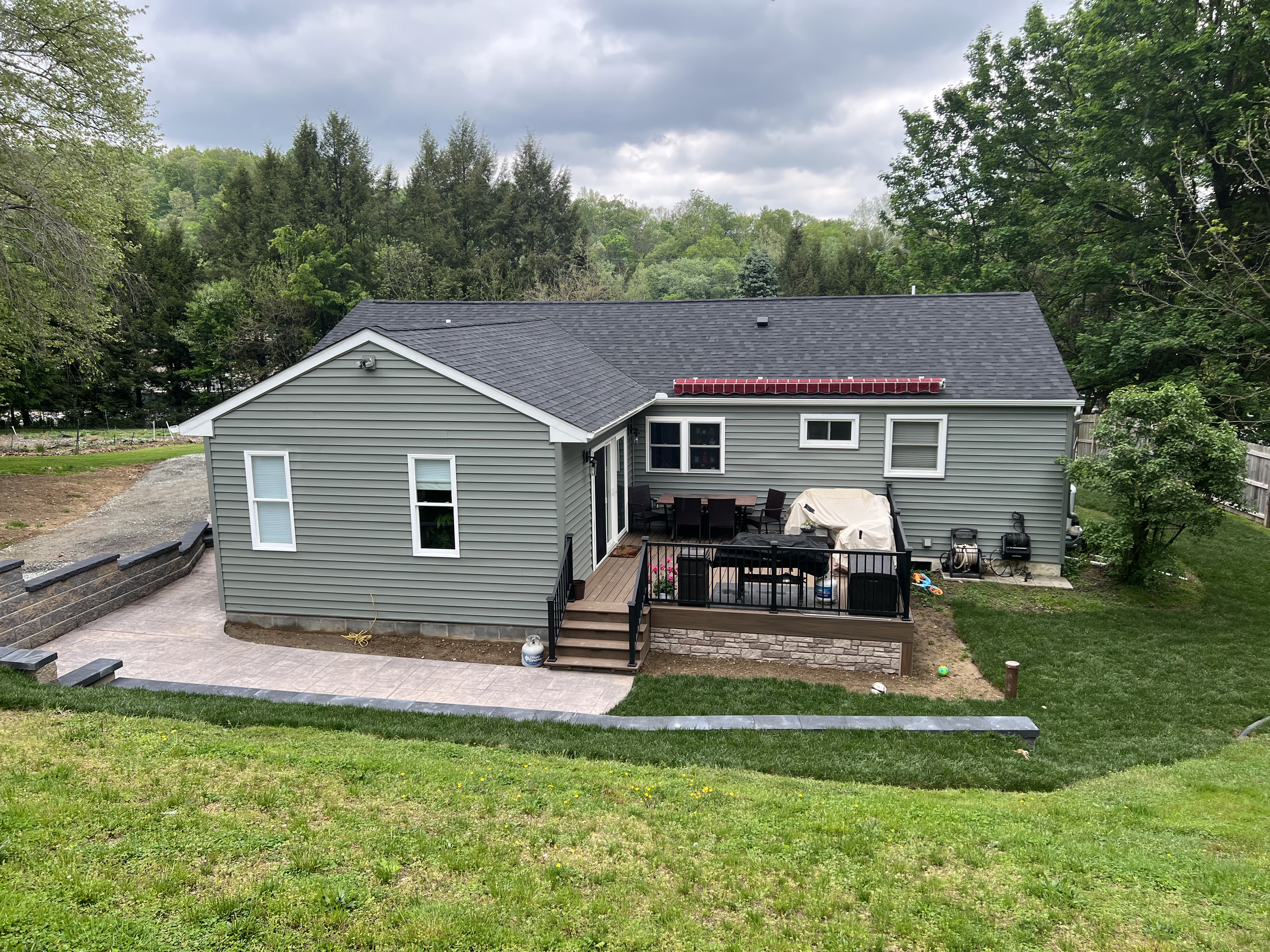 Rear view with new deck, addition, retaining wall, and patio